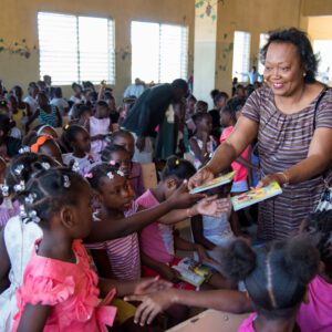 Magda N. Victor, framkvæmdastjóri Biblíufélagsins á Haítí að gefa jólabækur til barna í skóla á Haítí.